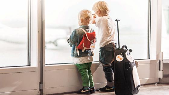 To barn venter foran vinduet på en flyplass.