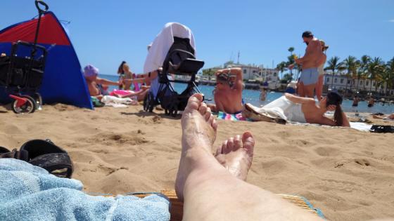 Solbadere på sandstrand. 
