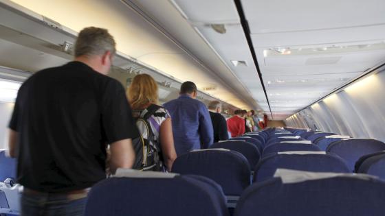 Personer gående i midtgang i flykabin.