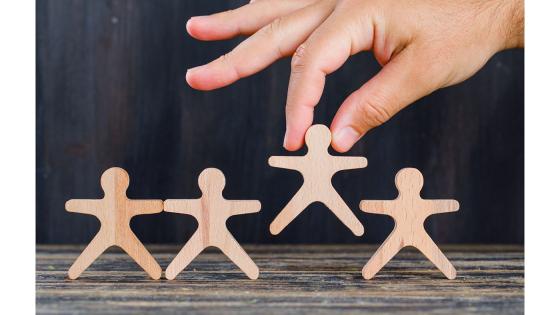 Hånd løfter en trefigur av et menneske.