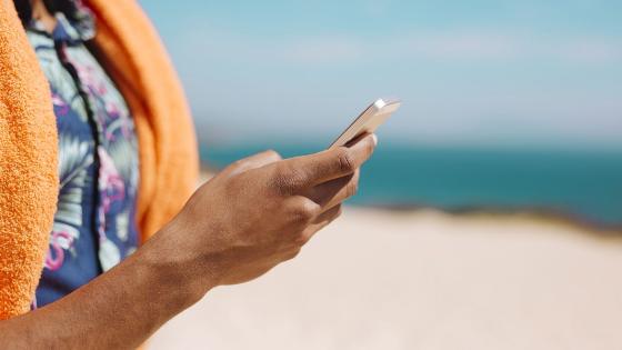 Turist med mobiltelefon på strand