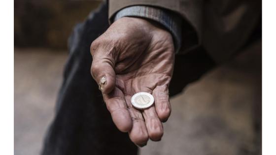 Hjemløs mann holder en mynt i hånden.
