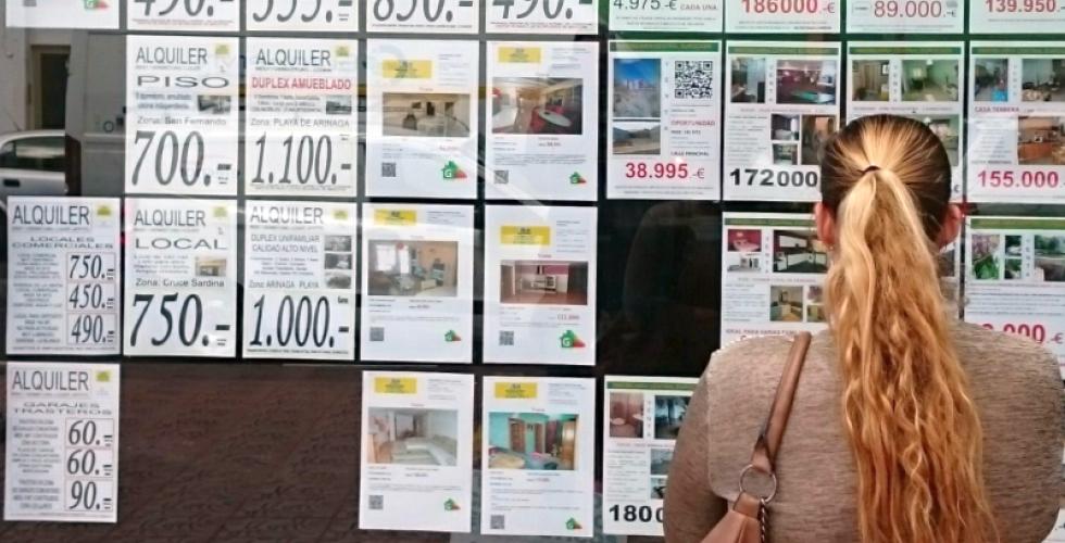 En kvinna studerar bostäder för uthyrning och till försäljning i ett fastighetsmäklarfönster på Gran Canaria