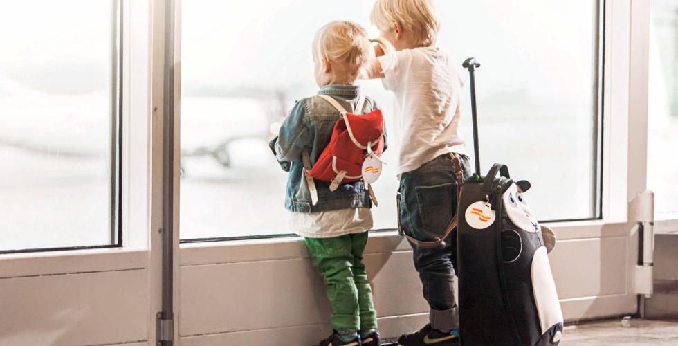 To barn venter foran vinduet på en flyplass.