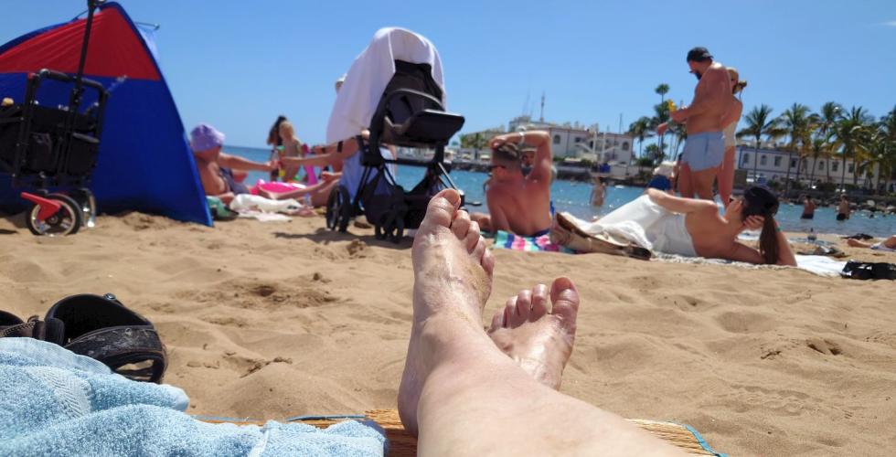 Solbadere på sandstrand. 
