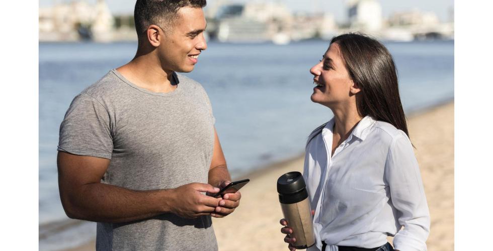 Mann og kvinne snakker sammen på en strand