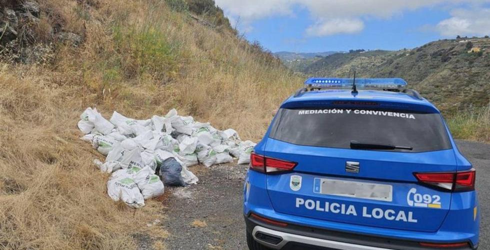 Politibil ved siden av søppelposer i naturområde.