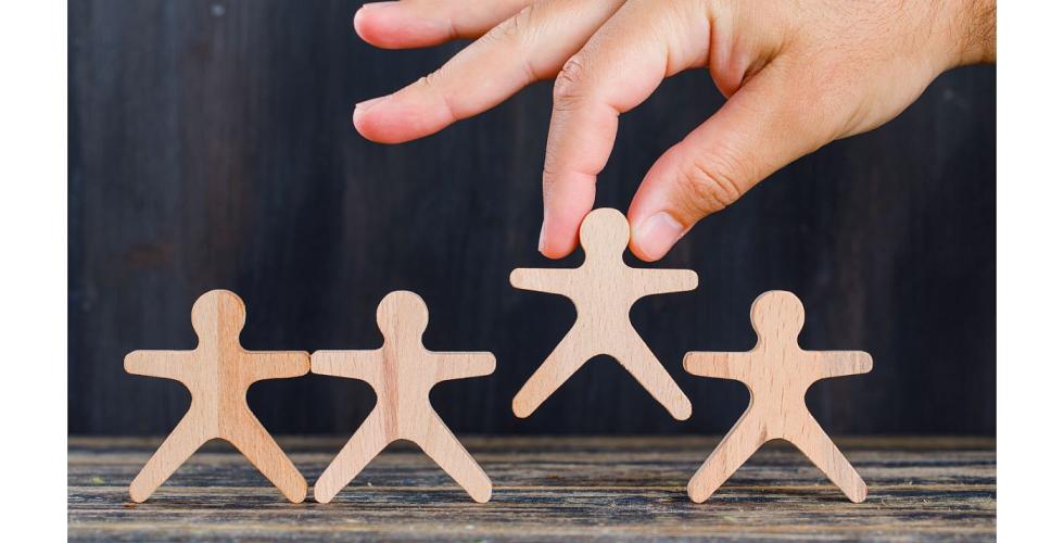 Hånd løfter en trefigur av et menneske.