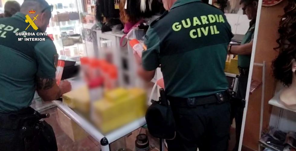 To politibetjenter undersøker varer i butikk.