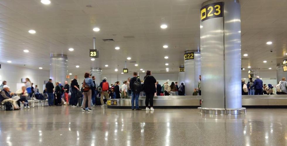 Passagerare väntar på sitt bagage på flygplatsen.