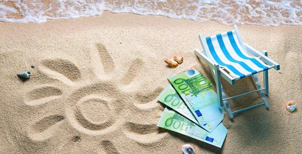 Sol tegnet i sand, solstol og eurosedler.